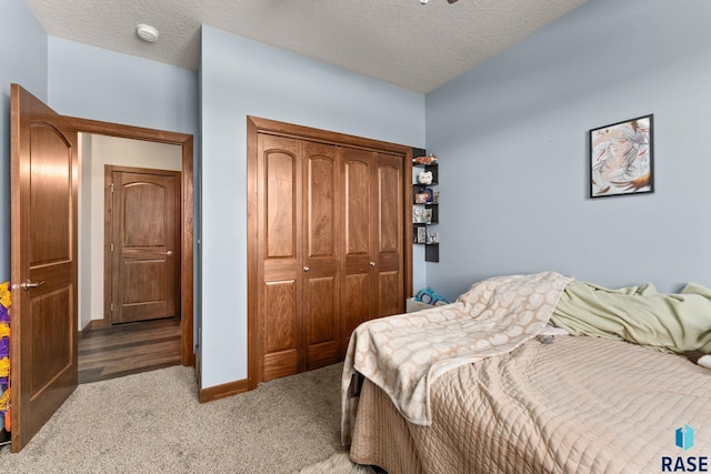 carpeted bedroom with a closet, baseboards, and a textured ceiling