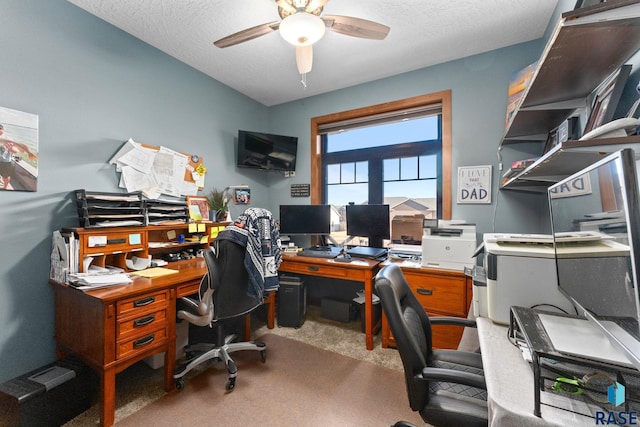 carpeted home office with a textured ceiling and a ceiling fan
