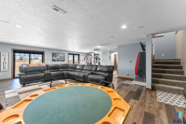 living room featuring dark wood-style flooring, baseboards, visible vents, and stairs