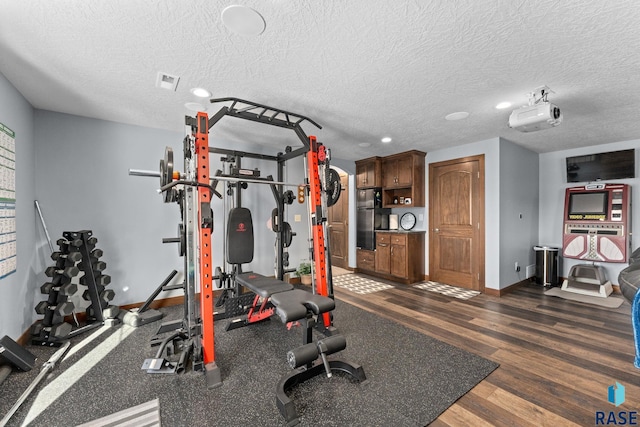 exercise room with visible vents, baseboards, dark wood-style floors, and a textured ceiling