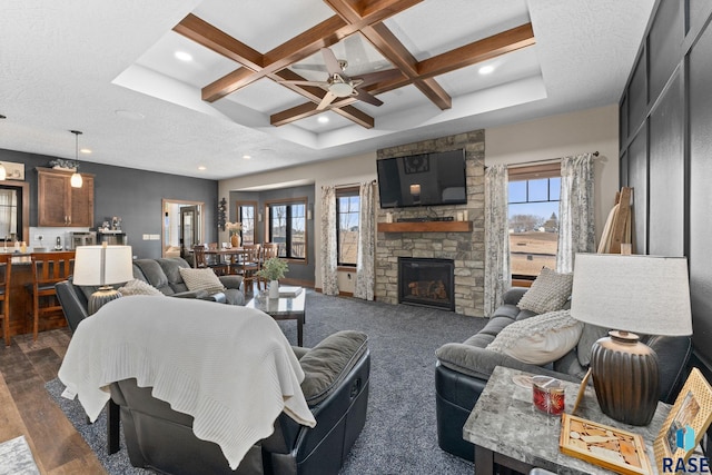 living area featuring beamed ceiling, ceiling fan, plenty of natural light, and coffered ceiling