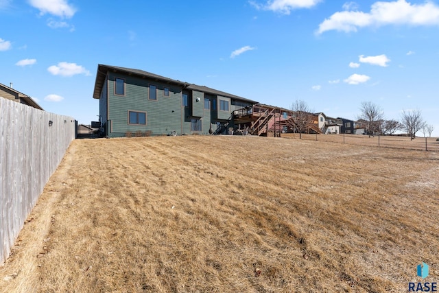 back of property featuring fence, a wooden deck, and stairs