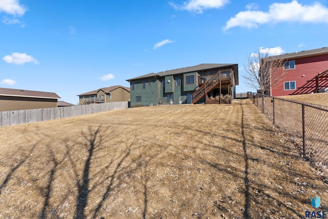 back of house featuring a fenced backyard, stairway, and a lawn