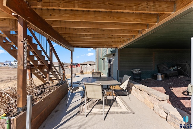 view of patio featuring fence, outdoor dining area, and stairs