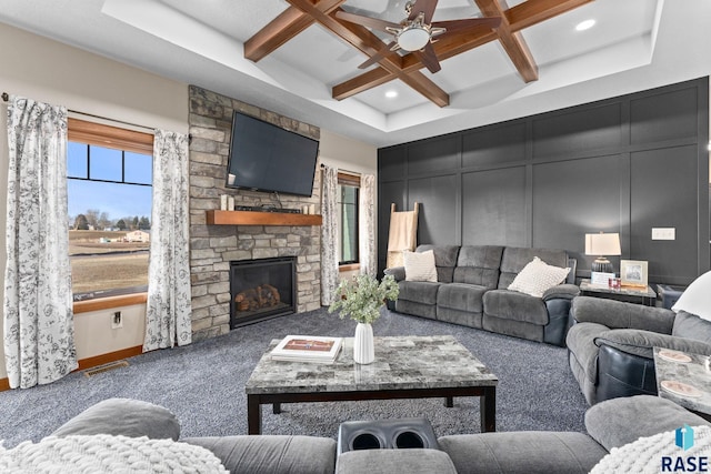 carpeted living room with a stone fireplace, coffered ceiling, beam ceiling, ceiling fan, and a decorative wall