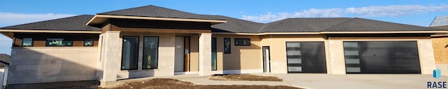 back of property with driveway, a shingled roof, and an attached garage