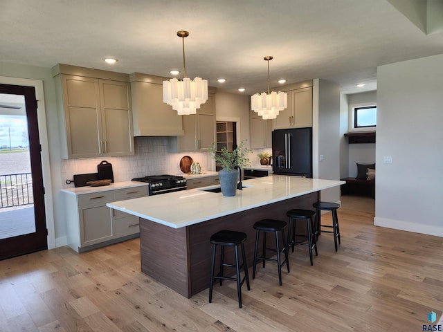 kitchen with light wood finished floors, an inviting chandelier, black appliances, and a breakfast bar
