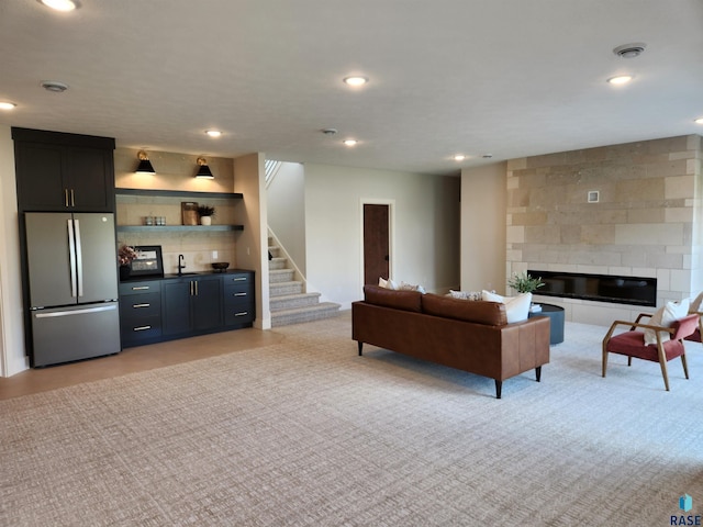 living room featuring light colored carpet, stairway, indoor wet bar, and recessed lighting