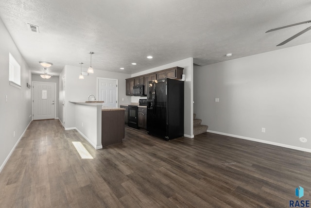 kitchen with light countertops, black appliances, dark brown cabinetry, and dark wood finished floors