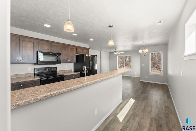 kitchen with hanging light fixtures, dark brown cabinetry, a textured ceiling, black appliances, and dark wood-type flooring