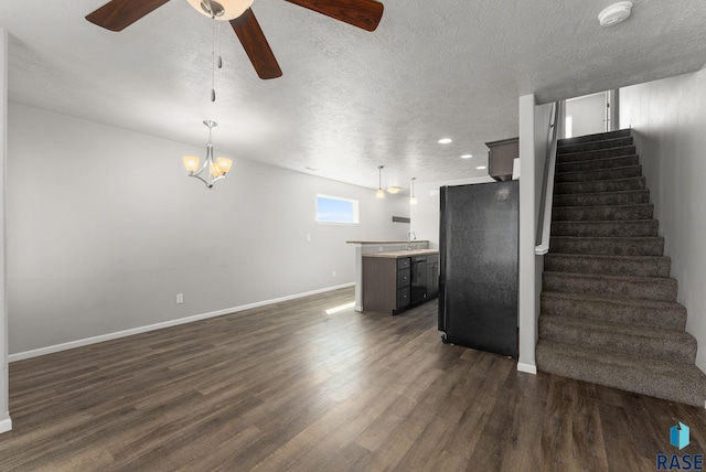 unfurnished living room featuring ceiling fan, a textured ceiling, stairway, dark wood-style flooring, and baseboards
