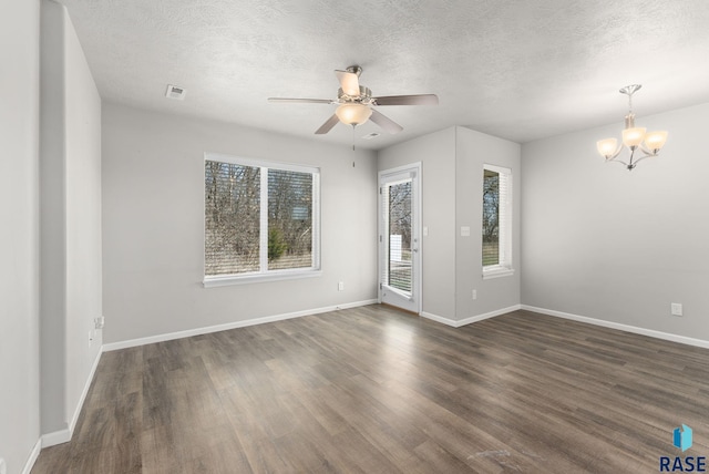 unfurnished room featuring baseboards, a textured ceiling, visible vents, dark wood finished floors, and ceiling fan with notable chandelier