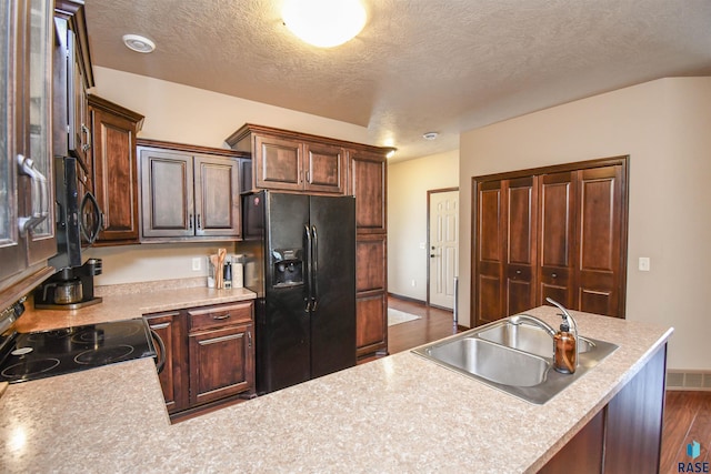 kitchen featuring visible vents, black appliances, dark wood-style flooring, light countertops, and a sink