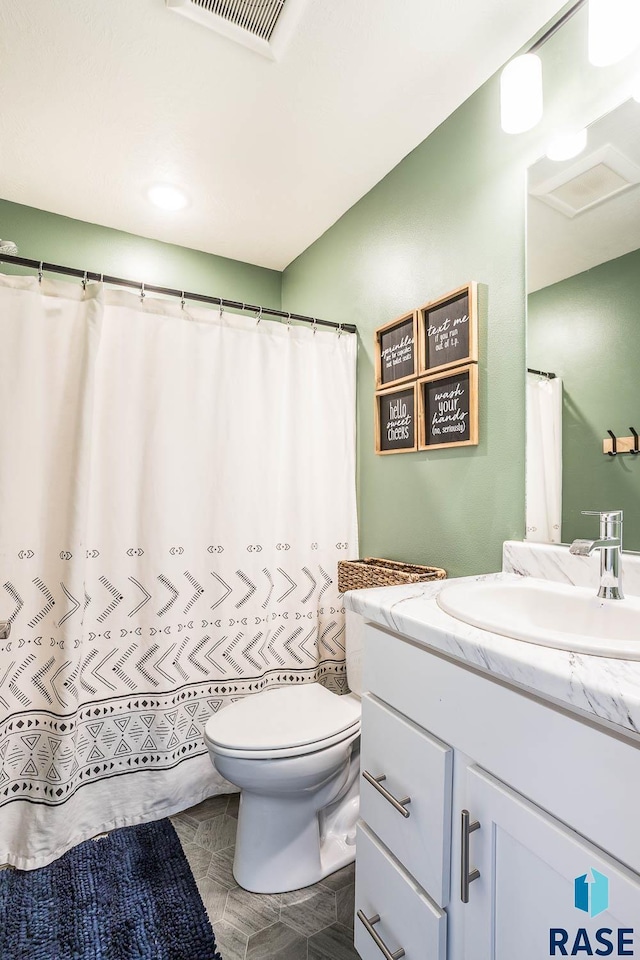 full bathroom with toilet, vanity, and visible vents