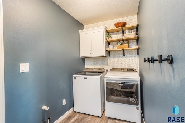 laundry room with light wood-style flooring, baseboards, cabinet space, and washer and clothes dryer