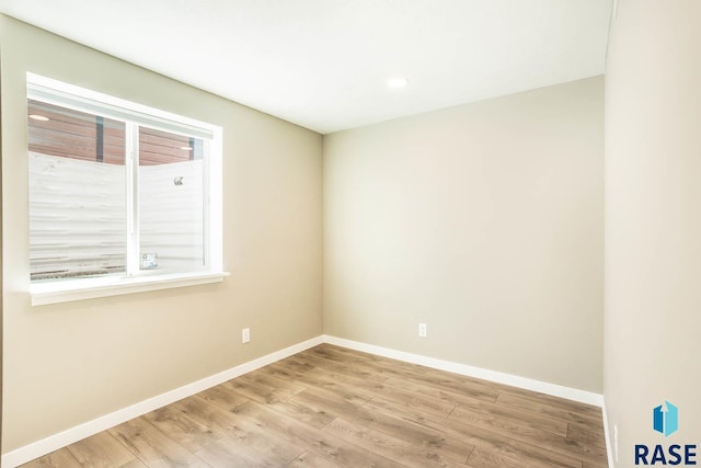 empty room featuring a healthy amount of sunlight, baseboards, and wood finished floors