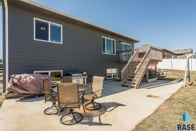 view of patio / terrace featuring outdoor dining area, a wooden deck, fence, and stairway