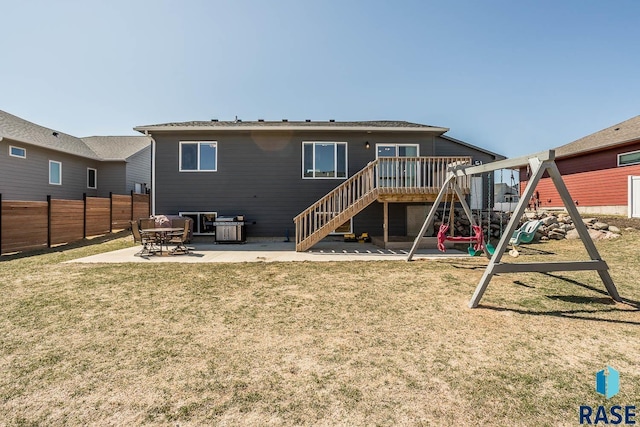 rear view of house featuring a playground, a patio area, fence, and a lawn