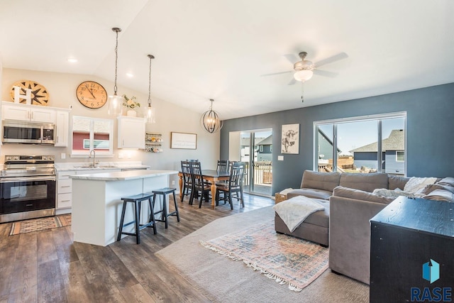 kitchen with a center island, white cabinetry, ceiling fan with notable chandelier, a breakfast bar area, and stainless steel appliances