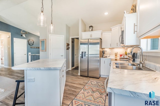 kitchen with a sink, light countertops, stainless steel appliances, a kitchen island, and a breakfast bar area