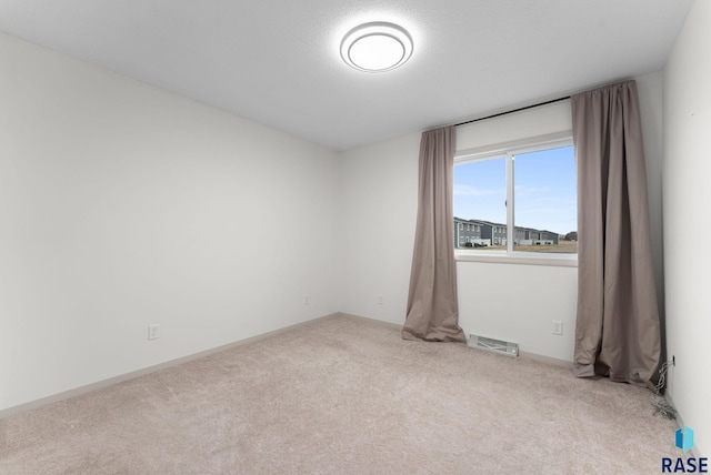 carpeted empty room featuring visible vents