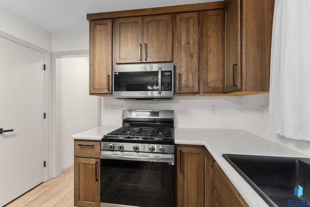 kitchen with light countertops, light wood-style floors, a sink, and stainless steel appliances