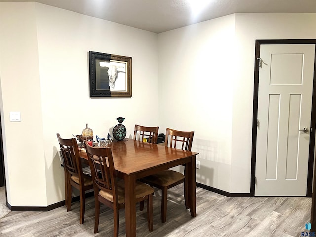 dining space with light wood-type flooring and baseboards
