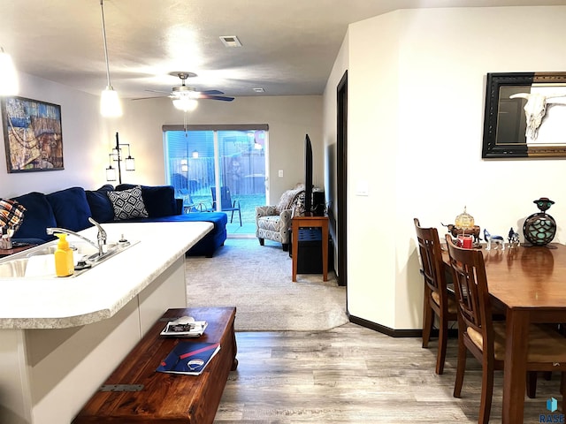 living area with visible vents, ceiling fan, light wood finished floors, and baseboards