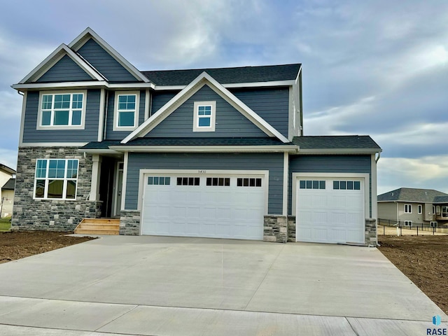 craftsman-style house with a garage, driveway, and stone siding