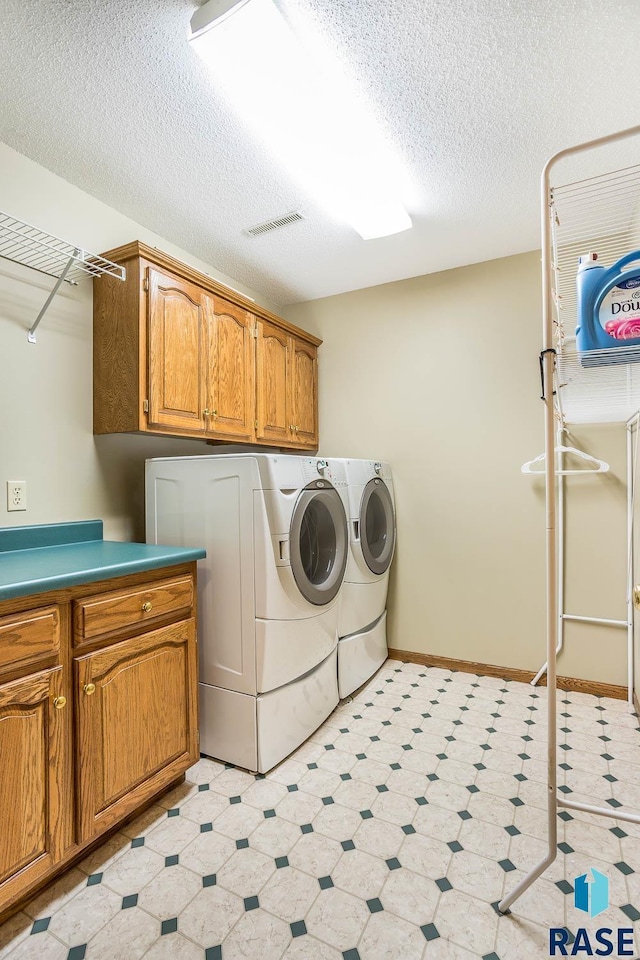 laundry room featuring visible vents, a textured ceiling, independent washer and dryer, cabinet space, and light floors