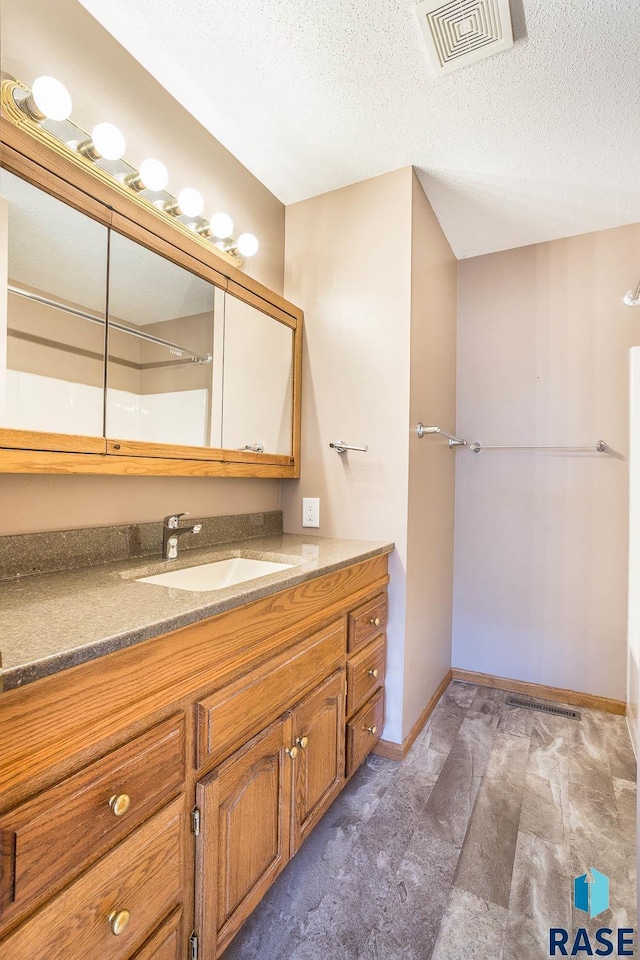 full bathroom featuring visible vents, baseboards, vanity, and a textured ceiling