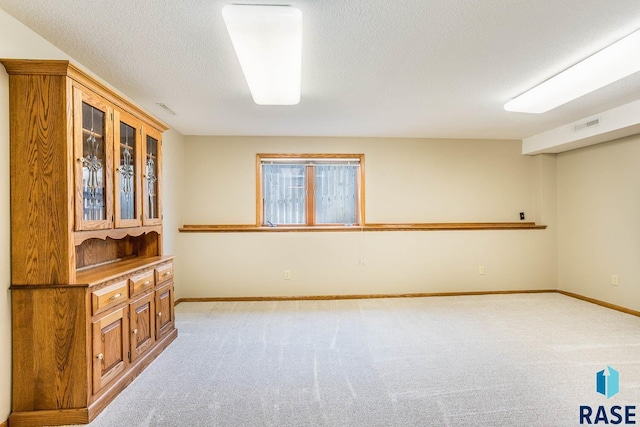 spare room featuring a textured ceiling, baseboards, visible vents, and carpet floors
