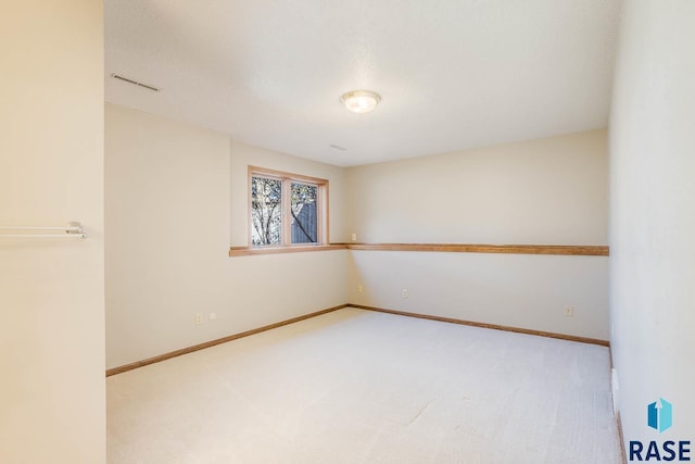 empty room featuring light carpet, visible vents, and baseboards