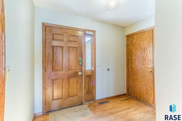 entryway featuring light wood-style flooring, baseboards, and visible vents
