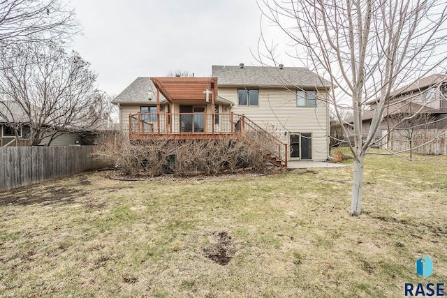 rear view of house featuring fence, a wooden deck, a lawn, and stairs