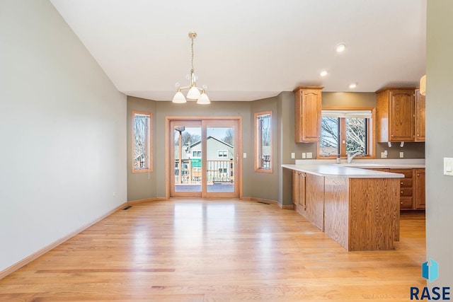 kitchen featuring light countertops, light wood-type flooring, a peninsula, and baseboards