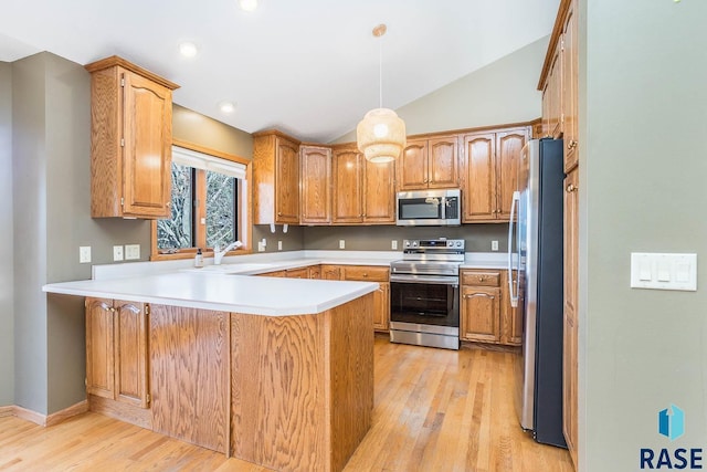 kitchen with appliances with stainless steel finishes, a peninsula, light wood-style flooring, lofted ceiling, and a sink