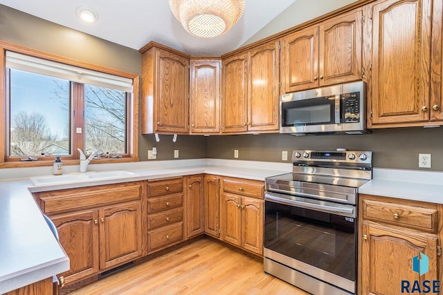 kitchen featuring brown cabinetry, a sink, and stainless steel appliances
