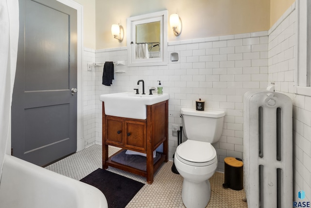 full bath featuring a wainscoted wall, toilet, tile walls, radiator heating unit, and vanity