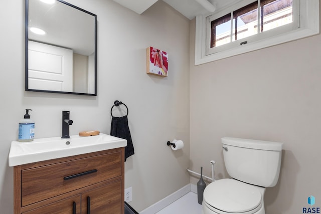 bathroom featuring toilet, vanity, and baseboards