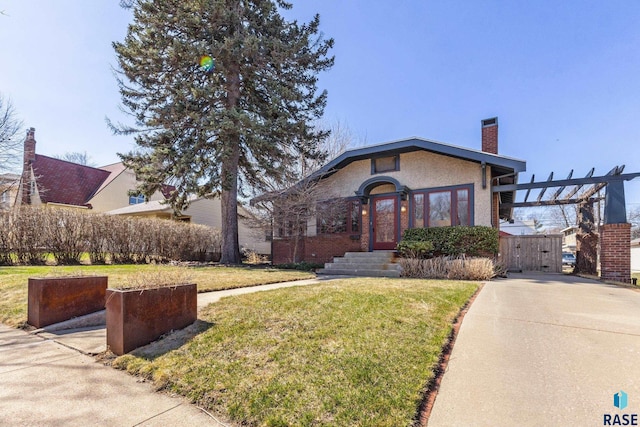 bungalow-style house with a chimney, a gate, a front yard, and stucco siding