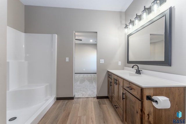 full bath with walk in shower, vanity, wood finished floors, and baseboards
