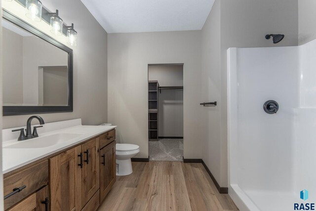 full bathroom with toilet, a shower, vanity, and wood finished floors