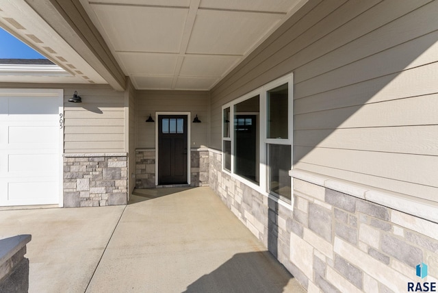 doorway to property with a garage and stone siding