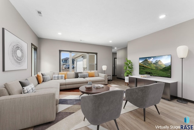 living room featuring light wood-type flooring, visible vents, and recessed lighting