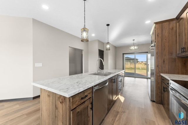 kitchen featuring light wood-style floors, appliances with stainless steel finishes, an island with sink, and a sink