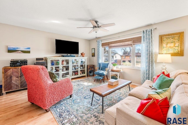 living room with a textured ceiling, wood finished floors, and ceiling fan