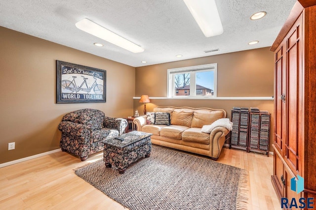 living room featuring visible vents, light wood finished floors, recessed lighting, and a textured ceiling