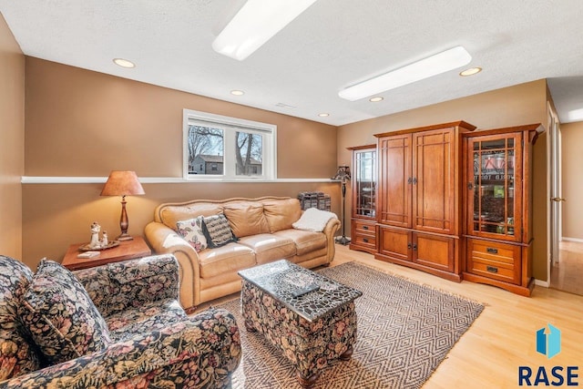 living area with recessed lighting, light wood-type flooring, and a textured ceiling