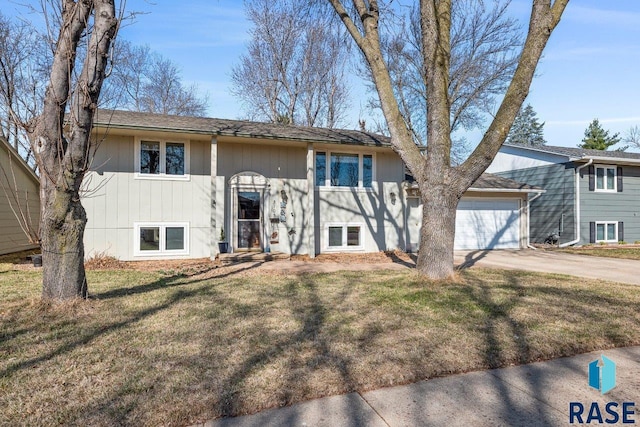 split foyer home featuring driveway, a garage, and a front lawn